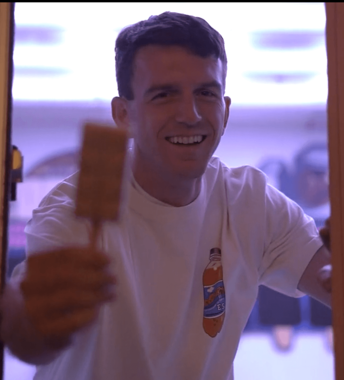 A Popston staff member smiling and reaching toward the camera with a popsicle, wearing a Popston-branded shirt.