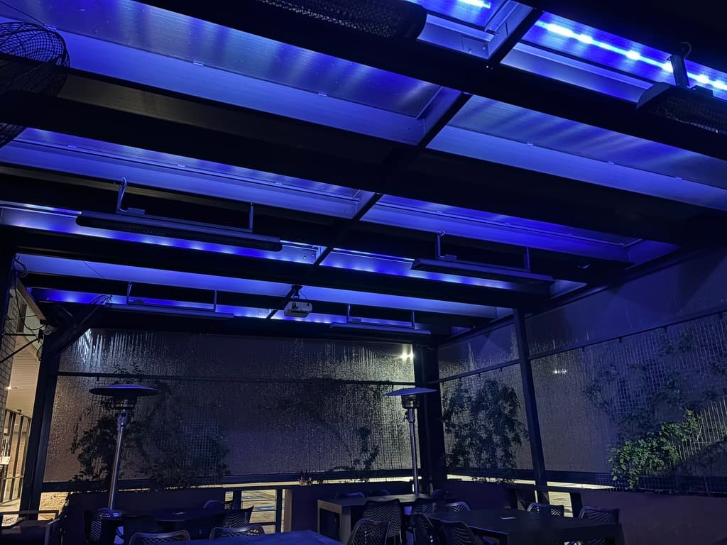 A teal-blue color state across the overhead linear LED grid, parking lot visible beyond.