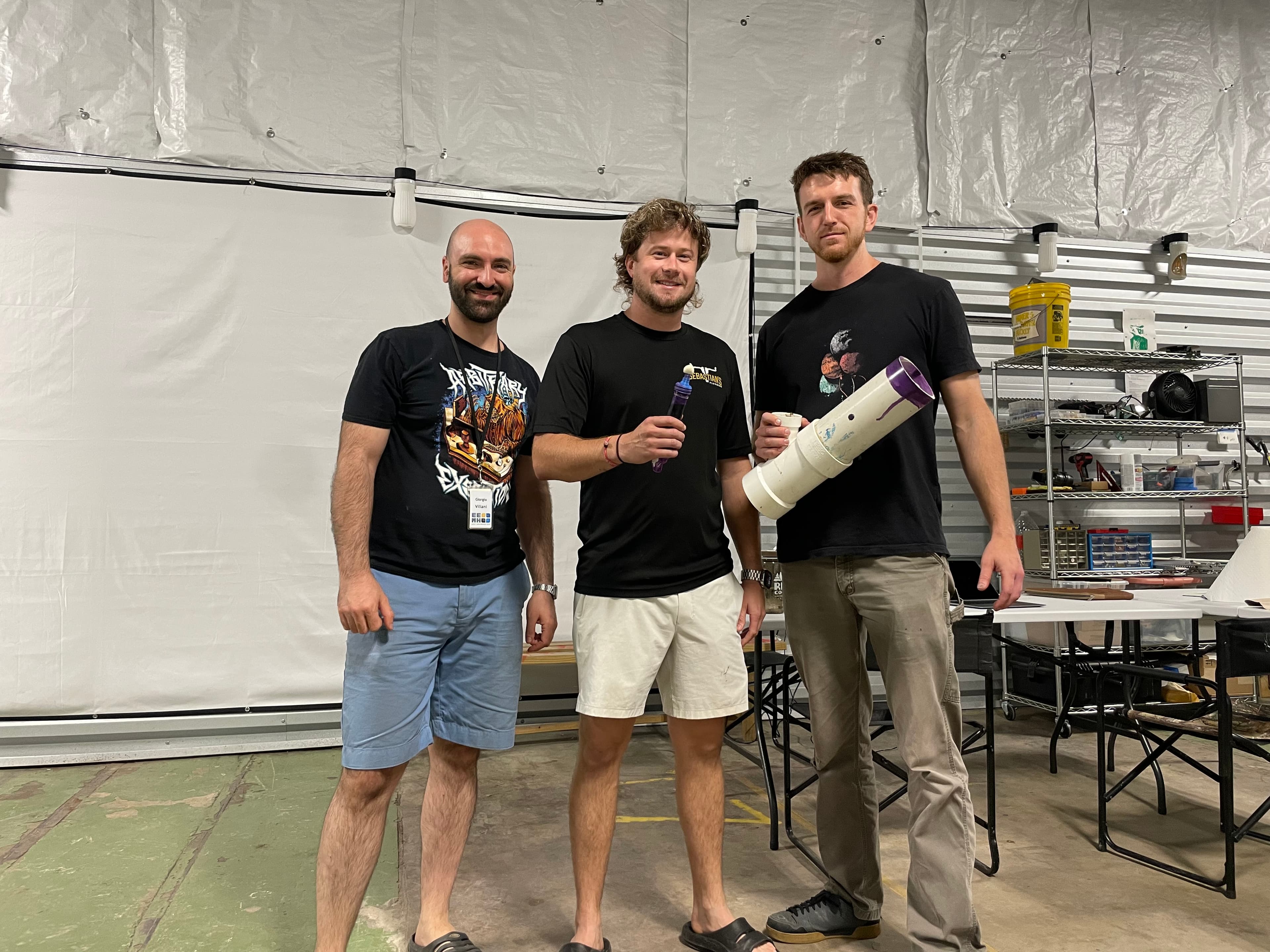Three people at a manufacturing facility holding a finished Primer Wand and its retail box.